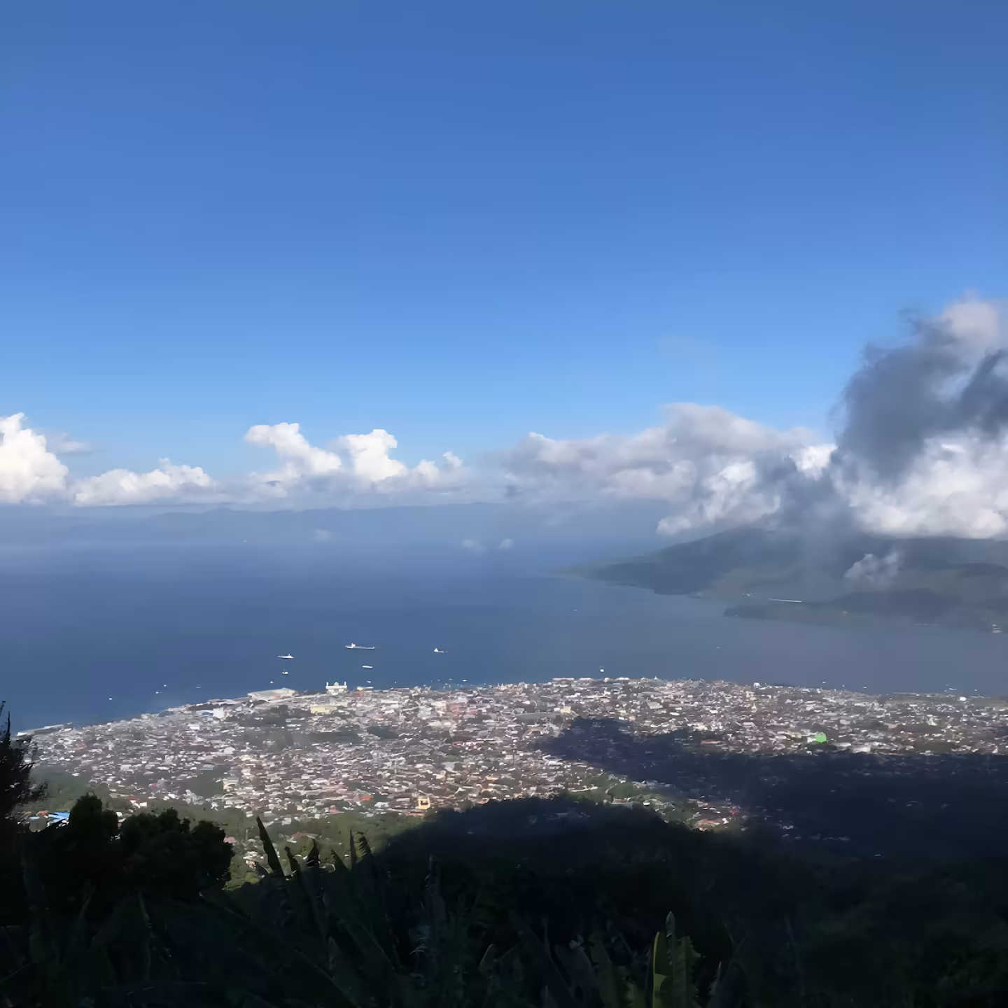 A breathtaking view of Ternate Island’s vibrant landscape, surrounded by the calm blue waters of the ocean, under a clear sky. Our tea company is located in this beautiful picturesque region.