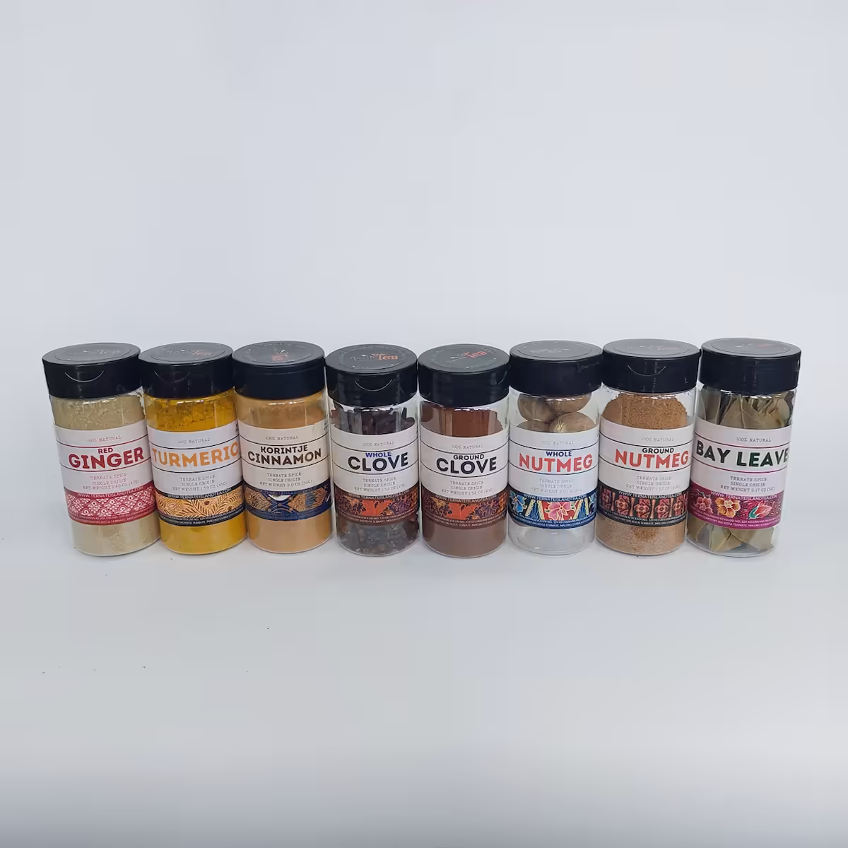 A lineup of our premium spice collection from Ternate Island, including Red Ginger, Turmeric, Korintje Cinnamon, Ground/Whole Clove, Ground/Whole Nutmeg, and Bay Leaves, beautifully displayed in jars to enhance your culinary creations